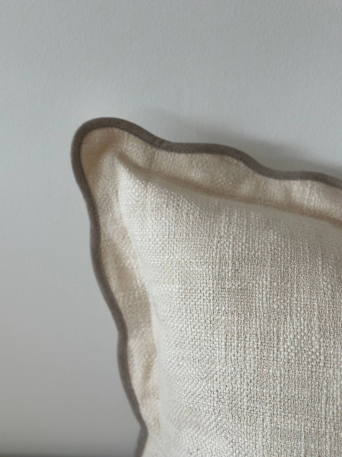 Close-up of a textured beige pillow against a light gray background