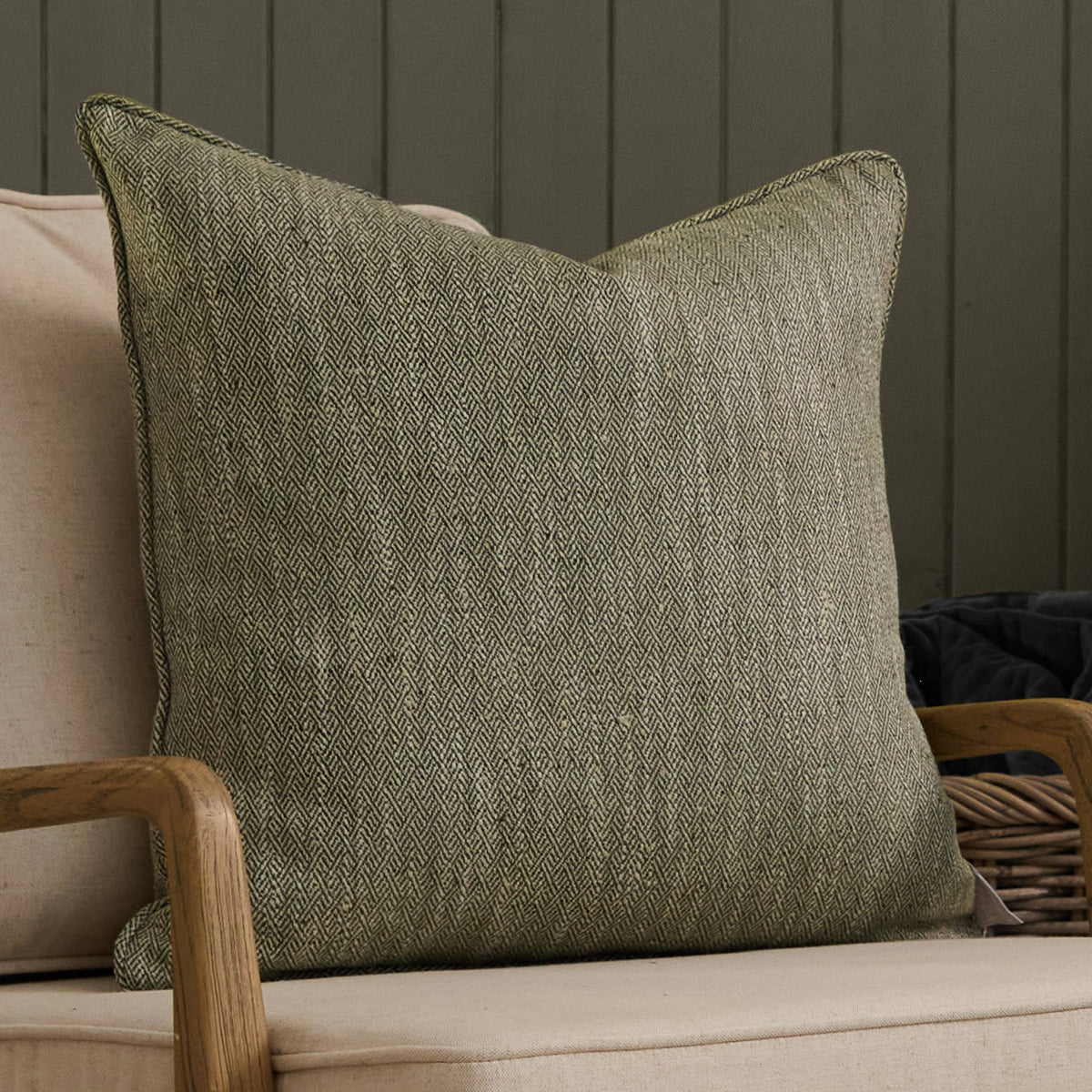 Green textured pillow on a beige sofa against a dark wooden panel wall