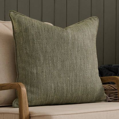 Green textured pillow on a beige sofa against a dark wooden panel wall