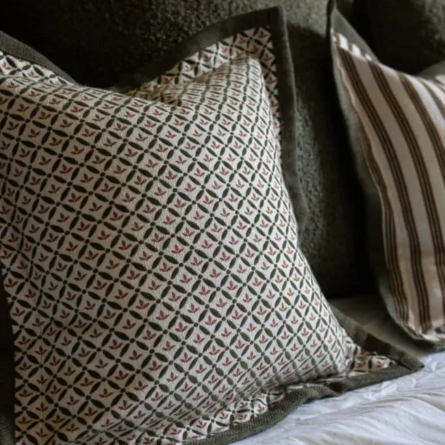 Patterned pillow on a bed with a striped pillow in the background