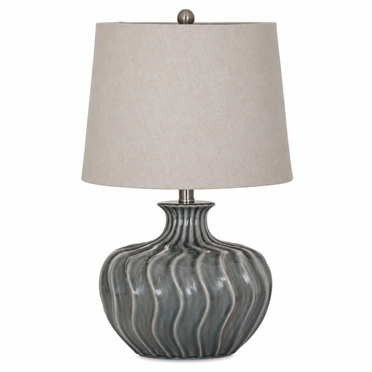 A table lamp with a ribbed, glossy gray ceramic base and a light beige linen drum shade, shown against a plain white background.